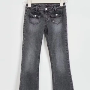 Grå jeans med fickdetaljer - Snygga grå jeans med en klassisk femficksdesign och vita knappar på framfickorna. Byxorna har en rak passform och är perfekta för en avslappnad stil. De har en diskret tvättad look som ger dem en trendig touch.