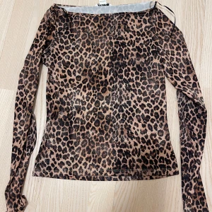 leopard topp från Monki - Säljer en snygg leopardmönstrad topp från Monki. Den har långa ärmar och en tight passform, perfekt för att sticka ut. Toppen är gjord i ett mjukt och stretchigt material.