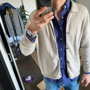 Beige kofta från Soft Goat - Säljer en stilren beige kofta från Soft Goat. Koftan har en klassisk design med knappar framtill och ribbade muddar vid ärmslut och nederkant. 100% cashmere!