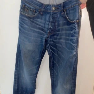 Blå jeans från G-Star RAW - Säljer ett par snygga blå jeans från G-Star RAW med en cool tvättad look. De har en klassisk femficksdesign och en knappgylf. Perfekta för en avslappnad stil.