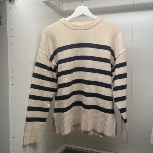 Stickad tröja från Zara - Säljer denna vita stickade tröjan med svarta ränder då den inte kommer till användning längre. Den är i storlek S men funkar för folk som har M. Det en en slits på båda sidorna av tröjan. Änvänd ett fåtal gånger