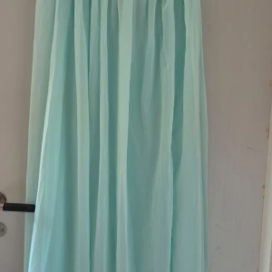 Ljusblå klänning från NLY Eve - Elegant ljusblå klänning från NLY Eve med vackra draperingar och en glittrig detalj framtill. Klänningen har en snörning i ryggen för en perfekt passform. Perfekt för speciella tillfällen.Använd endast 1 gg,Perfekt som  balklänning.