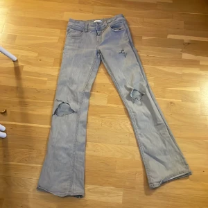 Grå jeans med hål - Säljer ett par grå jeans från Gina Tricot med slitna detaljer på knäna. Byxorna har en klassisk femficksdesign och en rak passform. Perfekta för en avslappnad stil. Lite slitna längst ner (se bild 4 eller 3). Kom privat för frågor!