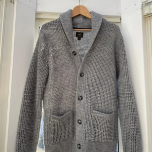 Grå stickad kofta från Next - Koftan är nästan helt ny, aldrig tvättad. Säljer pågrund av för stor . Koftan består av en ullmix.