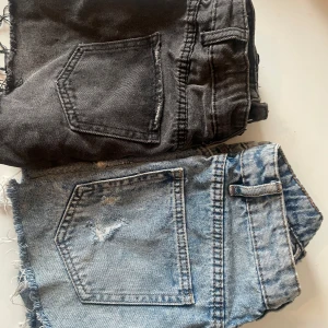 Jeansshorts från FB Sister och UNIQ - Säljer två par jeansshorts, ett par i ljusblå denim från FB Sister och ett par i svart denim från UNIQ. Båda har fransiga kanter och slitna detaljer för en cool look. Perfekta för sommardagar och festivaler! 200kr för båda!