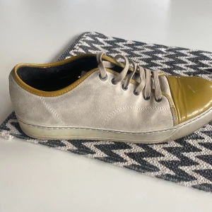 Lanvin - Snygga beige sneakers från Lanvin med gulddetaljer och snörning. Skorna har en rund tå och en stilren design som passar perfekt för en trendig look.