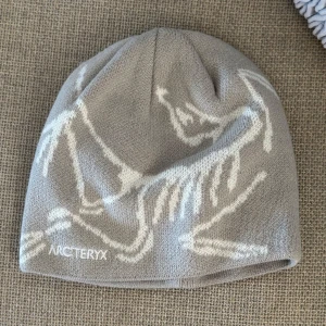 Grå mössa från Arc'teryx - Snygg grå mössa från Arc'teryx med vitt mönster. Köpt second hand med lappar kvar och har enbart använts av mig en-två gånger.