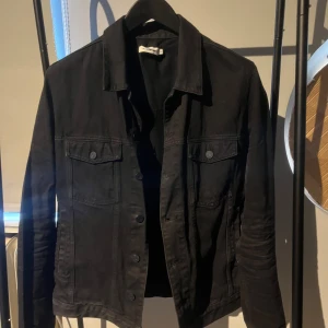 Mörk Jeansjacka Mauro Grifoni - Svart jacka med knäppning framtill och två bröstfickor med knappar. Jackan är av hög kvalitet och tillverkad i Italien. Storlek L men liten i passformen (M)