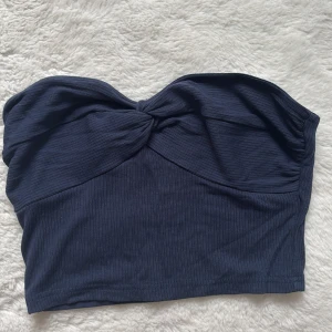 Mörkblå ribbad tubtopp - Snygg mörkblå tubtopp med ribbad textur och knytdetalj framtill. Perfekt för en stilren look.