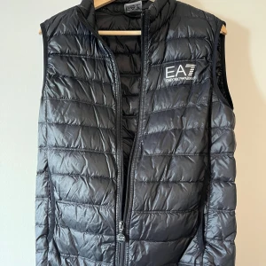 Svart dunväst från EA7 - Säljer en svart EA7 Emporio Armani dunväst i storlek M. Äkta vara och endast använd några få gånger, så den är i mycket fint skick. Perfekt för vår och höst.               Nypris 1545 - säljer för 850                                                     Pris kan diskuteras