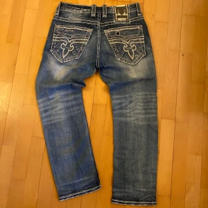 Rock Revival jeans! - Feta Rock revival jeans i hyfsat bra skick.         Midjan är W32 och 42 cm.                                                                    Längden är 99 cm.                                                                      Benöppningen är 21 cm.                                            Tveka inte att skriva om ni har några frågor och priset kan säkert diskuteras!!