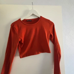 Orange croppad tröja från Zara - Snygg orange croppad tröja från Zara med långa ärmar. Perfekt för en trendig look. Enkel och stilren design som passar till många olika outfits.