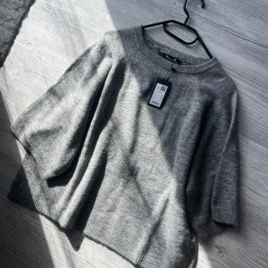 Grå stickad tröja från 157 - Säljer en stilren grå stickad tröja från 157. Tröjan har en lös passform med trekvartsärmar och rund halsringning. Perfekt för en avslappnad look. Passar bra till både jeans och kjol. Enbart prövad prislapp kvar 