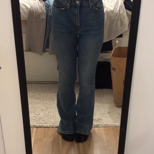 Blå bootcut jeans - Snygga blå bootcut jeans med hög midja. Perfekta för en avslappnad stil med en klassisk touch. De har en smickrande passform och är tillverkade i ett bekvämt denimtyg.
