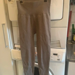 Bruna/beiga ribbade leggings - Dubbel storlek XS/S, super sköna, men är i minsta laget för mig! Jag drar small / medium. Säljer ett par bruna ribbade leggings i en mjuk och stretchig polyesterblandning. De har en hög midja och en tight passform som gör dem både bekväma och stiliga.