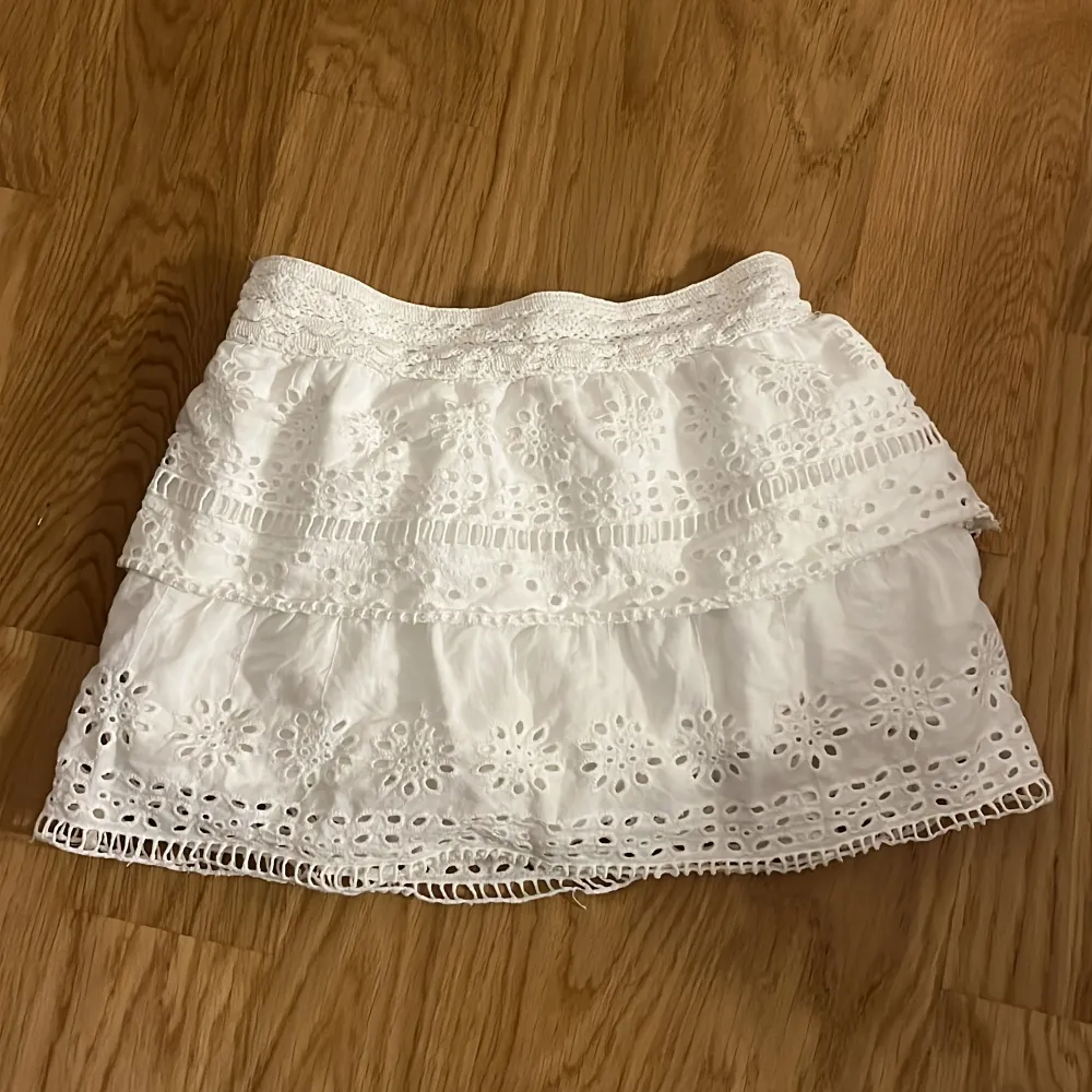 Söt vit kjol från Zara med broderade blommor och volanger. Perfekt för varma sommardagar. Den har en elastisk midja för extra komfort.. Hameet.