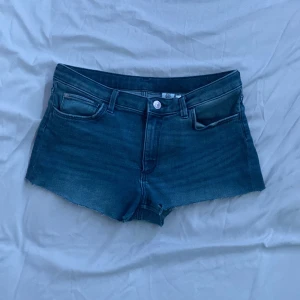 Blå jeansshorts från HM &Denim - Säljer ett par snygga blå lågmidjade jeansshorts från &Denim. De har en klassisk femficksdesign och är perfekta för sommardagar. Shortsen har en knapp och dragkedja framtill. Perfekt för en avslappnad stil! 💙