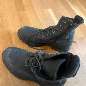 Svarta boots från Ecco - Säljer ett par robusta svarta boots från Ecco med snörning och dragkedja på sidan. Perfekta för utomhusaktiviteter med slitstark sula och bekväm passform. Lite repa med dragkedja på ett skor men det stör inte funktionen.