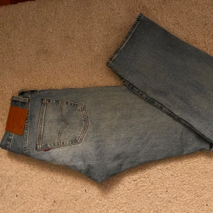 Levis premium 501 jeans  - Klassiska Levis 501 jeans i ljusblå denim. De har en rak passform och knappar i gylfen. Perfekta för en avslappnad stil med fem fickor och ikonisk läderpatch baktill.