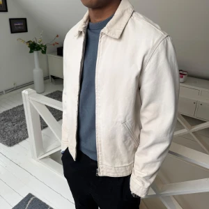 Vit jacka med klassisk krage - Snygg vit jacka i bomull med klassisk krage och dragkedja framtill. Jackan har en rak passform och diskreta sidfickor. Perfekt för dig som gillar en clean och stilren look.