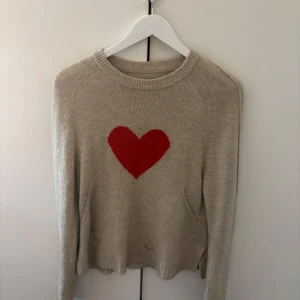 Beige stickad tröja med rött hjärta från Zadig & Voltaire - Superfin beige cashmere tröja från Zadig & Voltaire med ett stort rött hjärta på bröstet. Tröjan är i jätte bra skick och är jätte fin till våren🩷