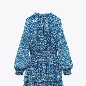 Blåmönstrad långärmad klänning  - Supersnygg blå och vit mönstrad klänning från Zara  med långa ärmar och smock i midjan. Klänningen har volangdetaljer och v-ringning framtill. 