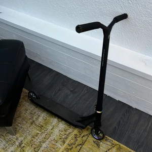 Svart kickbike - Säljer en svart kickbike med robust ram och T-format styre. Hjulen är små och slitstarka, perfekt för tricks och skatepark. Stilren design utan synliga dekaler eller mönster. Passar dig som gillar att åka sparkcykel och vill ha något enkelt men snyggt.