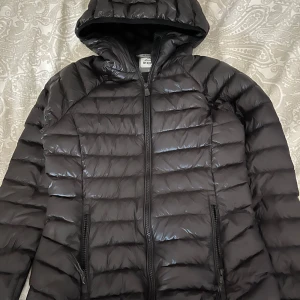 Svart pufferjacka från McKinley - Säljer en svart pufferjacka från McKinley då den har blivit för liten. Som ny