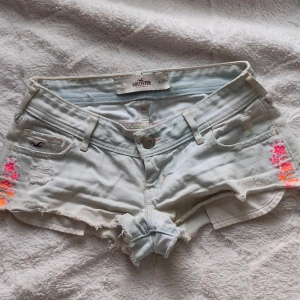 Jeansshorts med broderade blommor från Hollister💕 - Hej❣️ Säljer ett par jätte snygga ljustvätade lågmidjade jeansshorts från Hollister med slitna detaljer och broderade blommor i rosa och orange på sidorna.🌸 Storleken är w25 vilket jag skulle säga är xs/xxs. Säljer då dom tyvärr är för små för mig. Skriv om du har funderingar och frågor❣️❣️😊