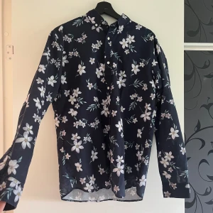 Mörkblå blommig skjorta från Jack & Jones - Fin skjorta från Jack & Jones. Den är sparsamt använd och är i fint skick! Skriv för fler bilder eller detaljer 😇