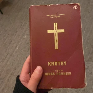 Knutby - Säljer boken 'Knutby' av Jonas Bonnier. Omslaget är vinrött med ett guldigt kors i mitten och text i guld. Perfekt för dig som gillar spännande romaner med verklighetsbakgrund.
