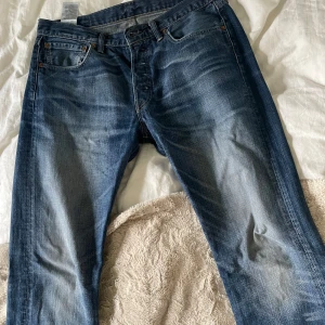Levi's 501 blå jeans - Klassiska blå Levi's 501 jeans med raka ben och normal passform. Perfekta för dig som gillar tidlös denimstil.