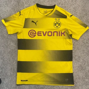 Borussia Dortmund 2017/18 fotbollströja  - Gul och svart randig Borussia Dortmund matchtröja från Puma med klubbmärke och sponsortryck på bröstet. 
