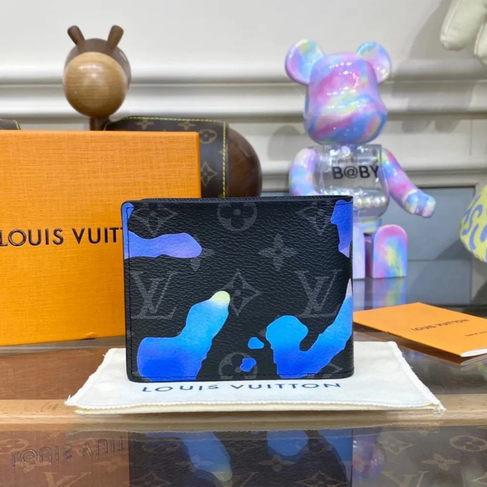 Snygg plånbok från Louis Vuitton i svart skinn med unikt blått, lila och vitt kamouflagemönster. Plånboken har diskret LV-logga och flera fack för kort och sedlar. Perfekt accessoar för dig som vill sticka ut.. Asusteet.