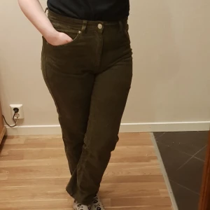 Olivgröna manchesterbyxor strl S  - Säljer ett par olivgröna manchesterbyxor med normal passform och raka ben. Byxorna har hög midja, klassiska fickor fram och bak samt stängs med dragkedja och knapp. Perfekta för dig som gillar retrostil och mjuka material. Det står dock 42 men dom är super små så en S lr en lite M mått 40cm x2 så 80cm runt om (inte höfter utan från navlen till navlen 2%elasian resten bomull 