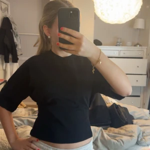 Svart croppad topp med knyt från Nelly - Säljer en svart croppad topp från Nelly i storlek XS. Toppen har korta ärmar och en snygg knytning i ryggen som ger en unik look. Perfekt till sommarens outfits och enkel att matcha med både jeans och kjol. Aldrig använt denna topp så den är i nyskick!🥰Nypris 249 kr