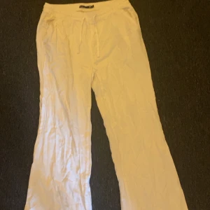 Vita linnebyxor från 157 - Säljer ett par vita linnebyxor från 157 med dragsko i midjan. Byxorna har raka ben och är perfekta för varma dagar. De är lätta och luftiga med en avslappnad passform.