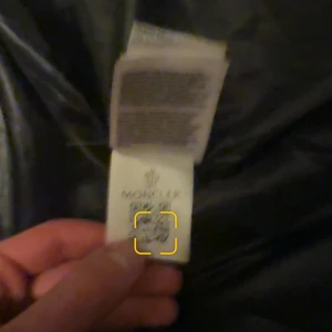 Svart vindjacka från Moncler med huva - Säljer en svart vindjacka från Moncler med huva och vit logotypdetalj på huvan. Jackan har dragkedja framtill och en Moncler-logga på bröstet .