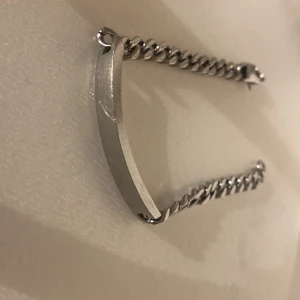 Stein less steal kedjearmband med platta - Stilrent armband i silverfärg med kraftig kedja och en slät, rektangulär platta framtill. Perfekt för att gravera in ett namn eller budskap. Lås med karbinhake. Passar dig som gillar klassiska accessoarer. Stein less steal material
