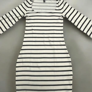 Vit och svart randig klänning från H&M Divided - Säljer en vit och svart randig klänning från H&M Divided. Klänningen har lång ärm, rund halsringning och är i ribbad bomull. Passformen är tight och längden är lagomlång . Perfekt för en stilren och enkel look. Skulle kunna användas som en tröja samt som en kort klänning. Köptes som en klänning.