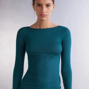 Mörkgrön långärmad topp - Säljer en mörkgrön långärmad topp med rund halsringning. Modellen är tight och enkel i designen, perfekt att styla med jeans eller kjol. Materialet känns mjukt och stretchigt.