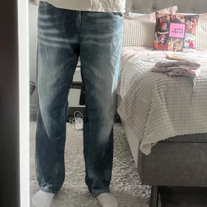 Blå jeansbyxor från Energie med raka ben, stl 34/34 - Säljer ett par blå Replay jeansbyxor med raka ben och klassisk femficksdesign. Jeansen har slitna detaljer och ljusa tvättade partier framtill och baktill. Märkeslogga på bakfickan och metallknapp framtill.