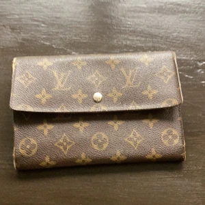 Louis Vuitton brun monogram plånbok - Säljer en klassisk brun plånbok från Louis Vuitton med ikoniskt monogrammönster och guldfärgad knapp. Plånboken har flera kortfack, sedelfack och myntfack med dragkedja. Utsidan är i präglat skinn och insidan i slätt brunt skinn. Perfekt för dig som gillar lyxiga accessoarer.    Celine skärp fina och välbehållna.