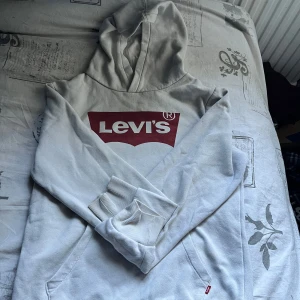  Levis hoodie  - Säljer en vit hoodie från Levi's med den klassiska röda loggan framtill. Tröjan har huva, känguruficka och ribbade muddar. Perfekt för dig som gillar en clean och stilren look med streetkänsla.