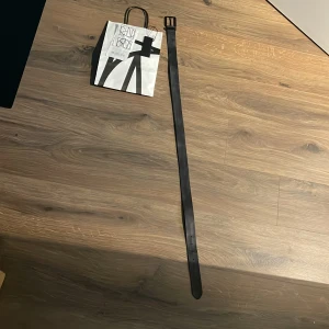 Svart skärp i skinn från Replay - Stilrent svart bälte från Replay i äkta skinn med matt svart metallspänne och Replay-logga vid fästet. Bältet har en klassisk, rak form och passar perfekt till jeans eller kostymbyxor. Snygg detalj som lyfter din outfit.