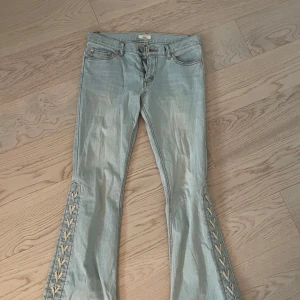 Ljusblå bootcut jeans med snörning - Säljer ett par ljusblå bootcut jeans med snygg snörningsdetalj längs utsidan av benen. Så fina men lite för små för mig tyvärr! Jag är 172 och tycker att de är lite korta och skulle säga att storleken är mellan 34-36