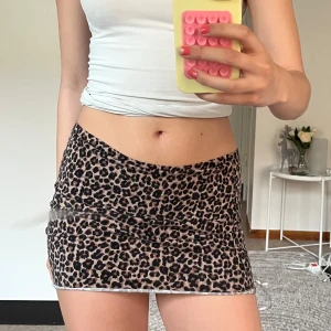 Leopardmönstrad kortkjol  - Superfin kortkjol med leopardmönster i bruna och svarta toner. Kjolen är figurnära och har en lätt transparent mesh-look med stretchigt material. Perfekt för dig som vill sticka ut och köra på en trendig vibe. (Originellt en klänning som jag klippt) stretchig så passar flera storlekar.