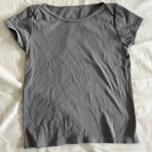 Grå basic kortärmad topp - Enkel och stilren grå topp med rund halsringning och korta ärmar. Perfekt att matcha med jeans eller kjol för en clean look. Mjuk och skön i bomullsmaterial, passar dig som gillar minimalistisk stil.