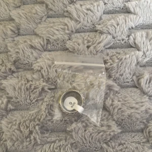 Silverfärgad ring med flätad kant - Säljer en snygg silverfärgad ring i storlek 9. Ringen har en cool flätad kant runt om som ger den en unik och trendig look. Perfekt accessoar för att lyfta din outfit och ge lite extra edge.