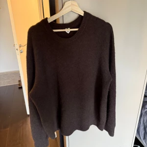 Mörkbrun stickad tröja Arket M - Mysig mörkbrun stickad tröja med rund halsringning och långa ärmar. Perfekt för kyliga dagar och enkel att matcha med jeans. Tröjan har en klassisk, avslappnad passform och ribbade muddar vid ärmslut och nederkant. Köpt på Arket för 750 och aldrig använd.